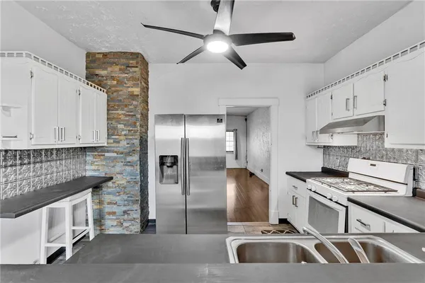 a kitchen with stainless steel appliances kitchen island granite countertop a sink and a refrigerator