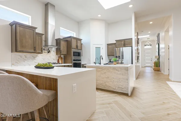 a kitchen with stainless steel appliances kitchen island granite countertop a refrigerator and a sink