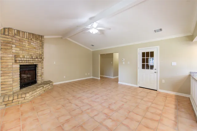a view of an empty room with chandelier fan and fire place