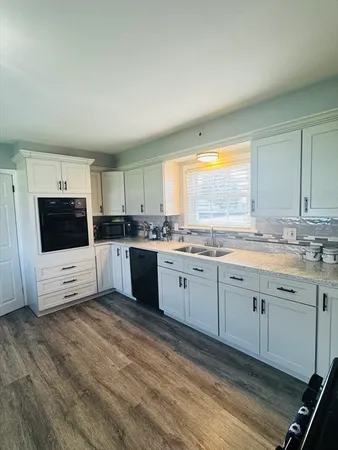 a large kitchen with stainless steel appliances granite countertop a stove a sink and a microwave