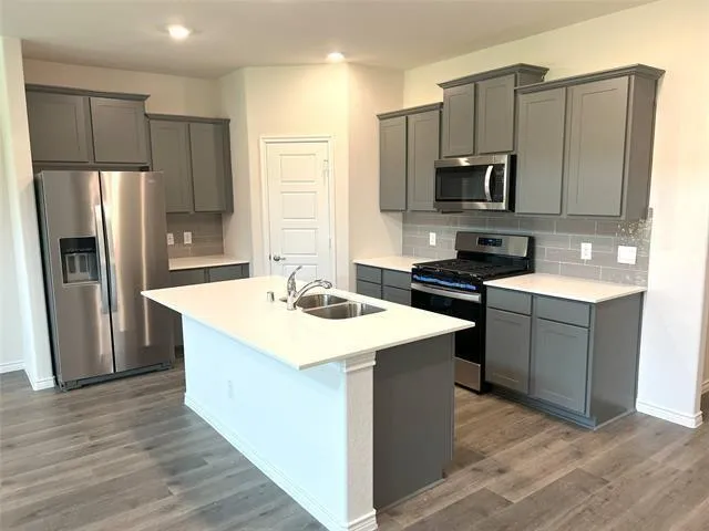 a kitchen with kitchen island granite countertop a sink refrigerator and microwave