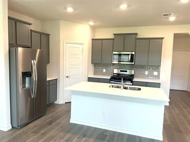 a kitchen with kitchen island a refrigerator sink and stove