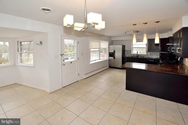 a kitchen with granite countertop a stove a refrigerator a sink a dining table and chairs with wooden floor