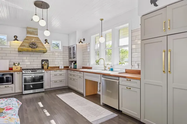 a large kitchen with stainless steel appliances granite countertop a stove a sink and a refrigerator