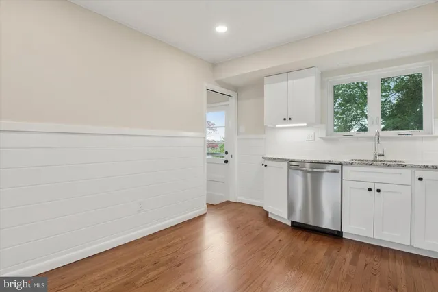 a view of a kitchen with a sink and dishwasher with wooden floor