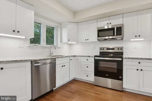 a kitchen with granite countertop white cabinets stainless steel appliances and a sink