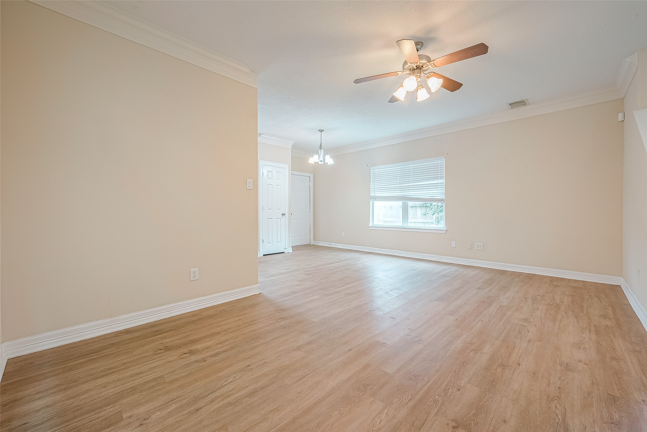 10355 Panther Point Drive Houston, TX 77099 - Photo 13 of 44 Spacious, well-lit room with light wood flooring, neutral walls, and a ceiling fan. Features crown molding and ample natural light from a large window. Ideal for a living or dining area.