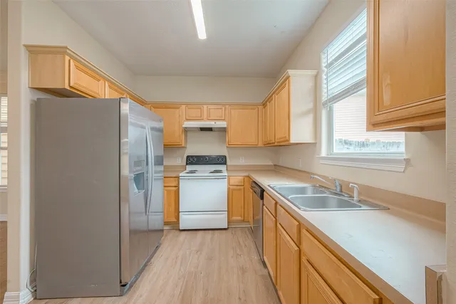 a kitchen with a sink cabinets stainless steel appliances and a window