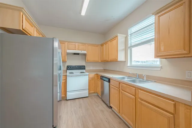 a kitchen with a sink cabinets stainless steel appliances and a window