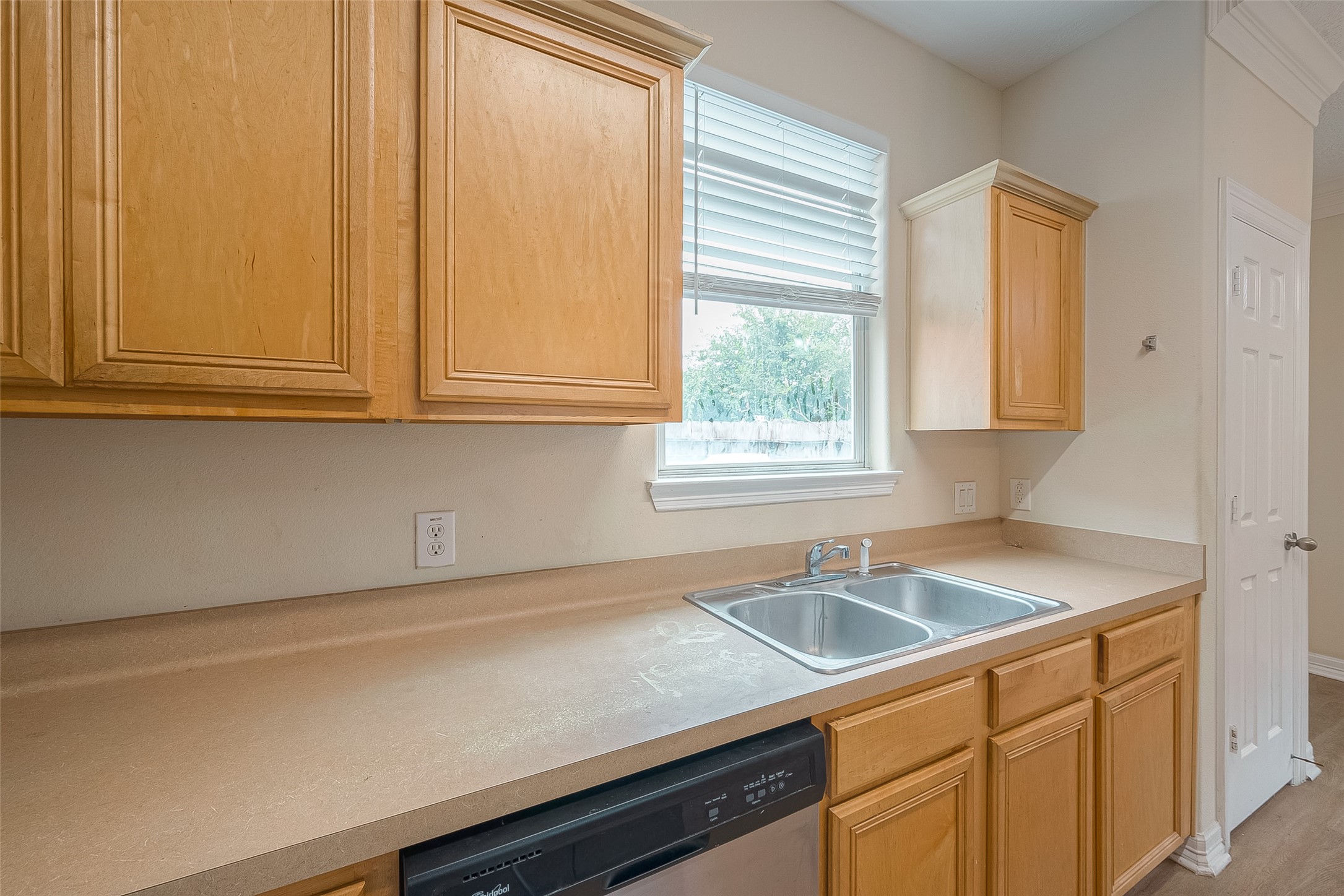10355 Panther Point Drive Houston, TX 77099 - Photo 20 of 44 This kitchen features light wood cabinetry, a double stainless steel sink, and a dishwasher. There's a window above the sink providing natural light, and ample counter space for meal preparation.