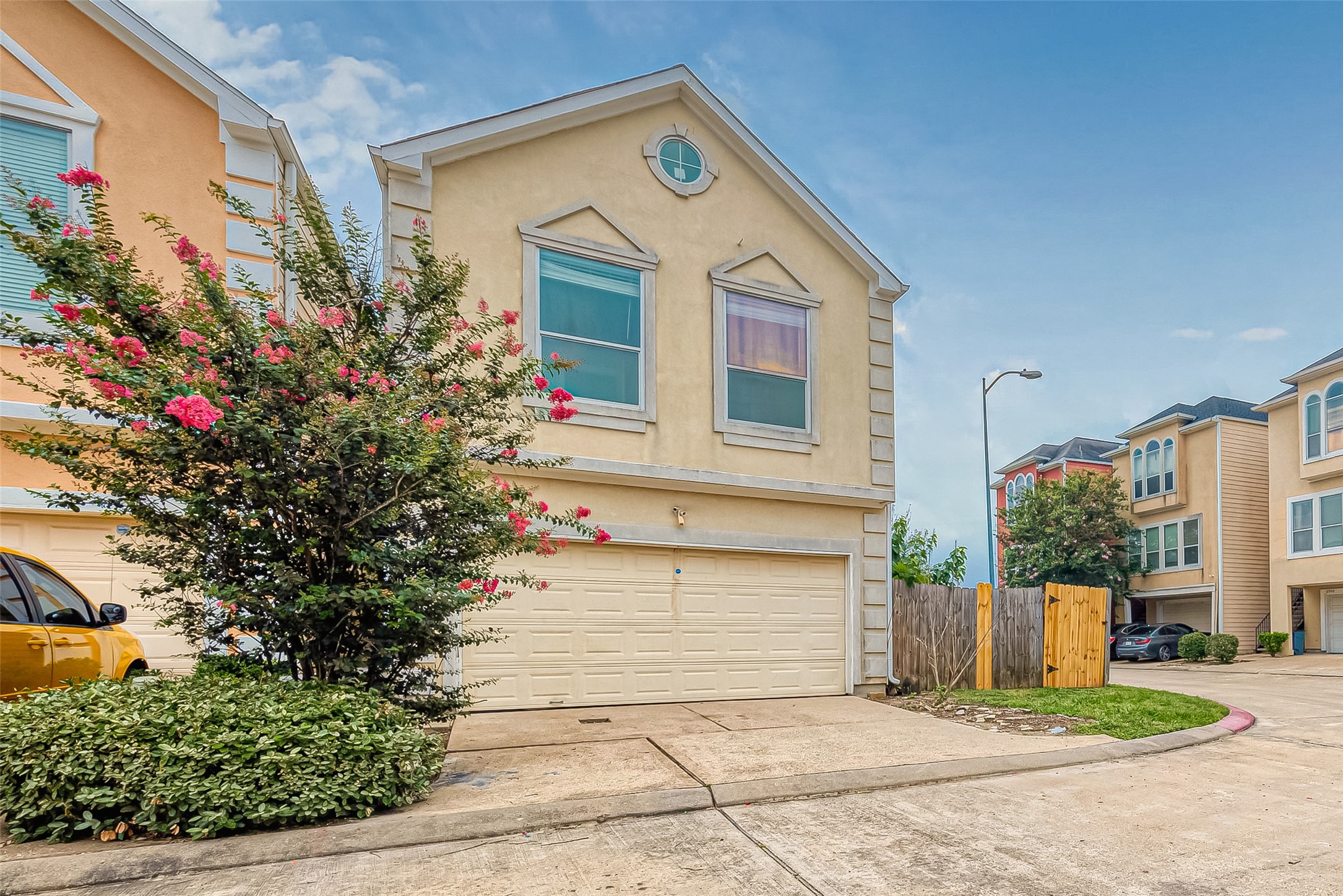 10355 Panther Point Drive Houston, TX 77099 - Photo 2 of 44 This is a two-story home with a stucco exterior located in a residential neighborhood. It features a two-car garage and a small front yard with flowering shrubs. The street is lined with similar style homes, and there's a wooden fence on one side.