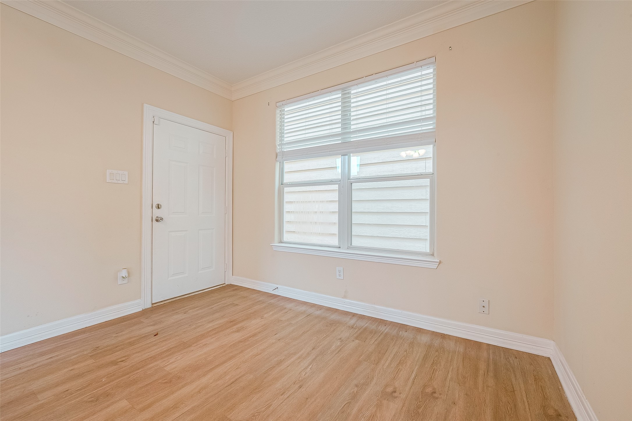 10355 Panther Point Drive Houston, TX 77099 - Photo 21 of 44 This photo shows a bright room with light-colored walls and wood flooring. It has a large window with blinds and a white door, offering natural light and a cozy ambiance. Perfect for a small office or reading nook.