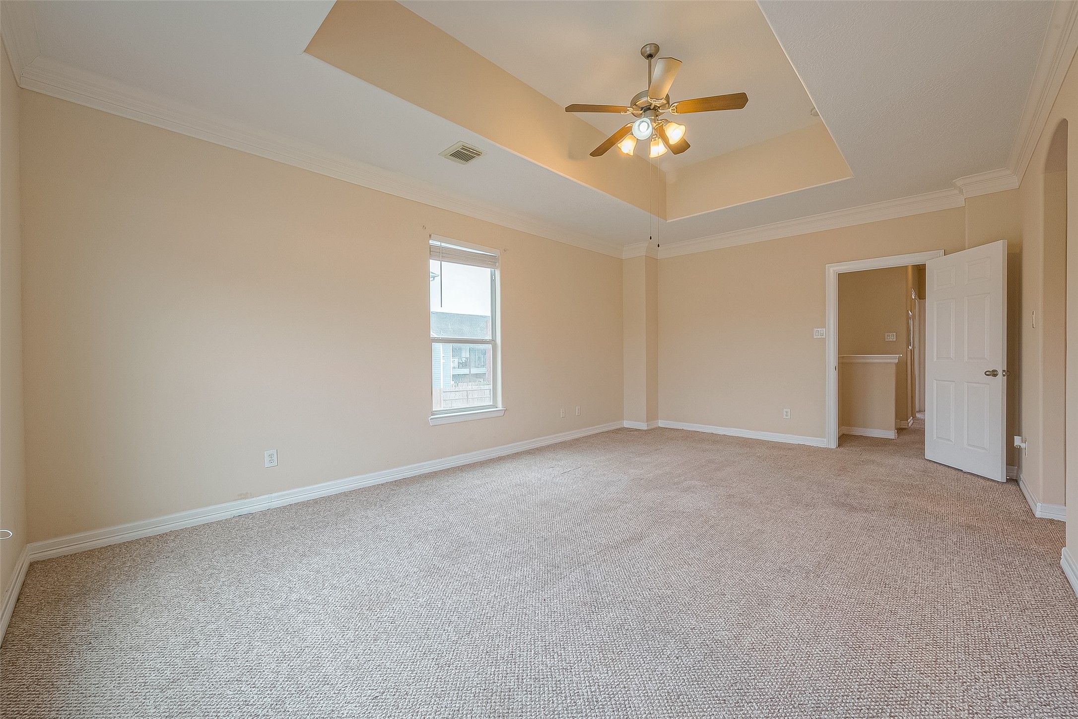 10355 Panther Point Drive Houston, TX 77099 - Photo 24 of 44 This spacious room features neutral-toned walls, a plush carpet, and a tray ceiling with a ceiling fan. Natural light filters through a single window, and there is an open doorway leading to an adjacent area.