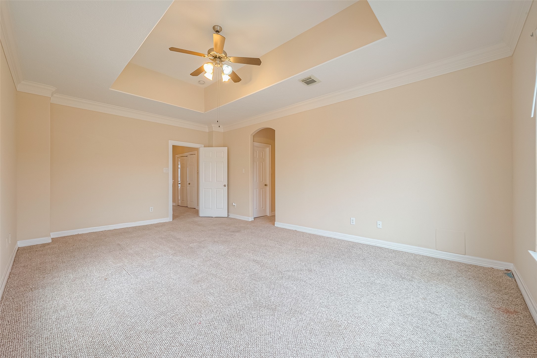 10355 Panther Point Drive Houston, TX 77099 - Photo 25 of 44 Spacious bedroom with a tray ceiling, neutral walls, and soft carpeting. Features a ceiling fan and ample natural light from a large window.