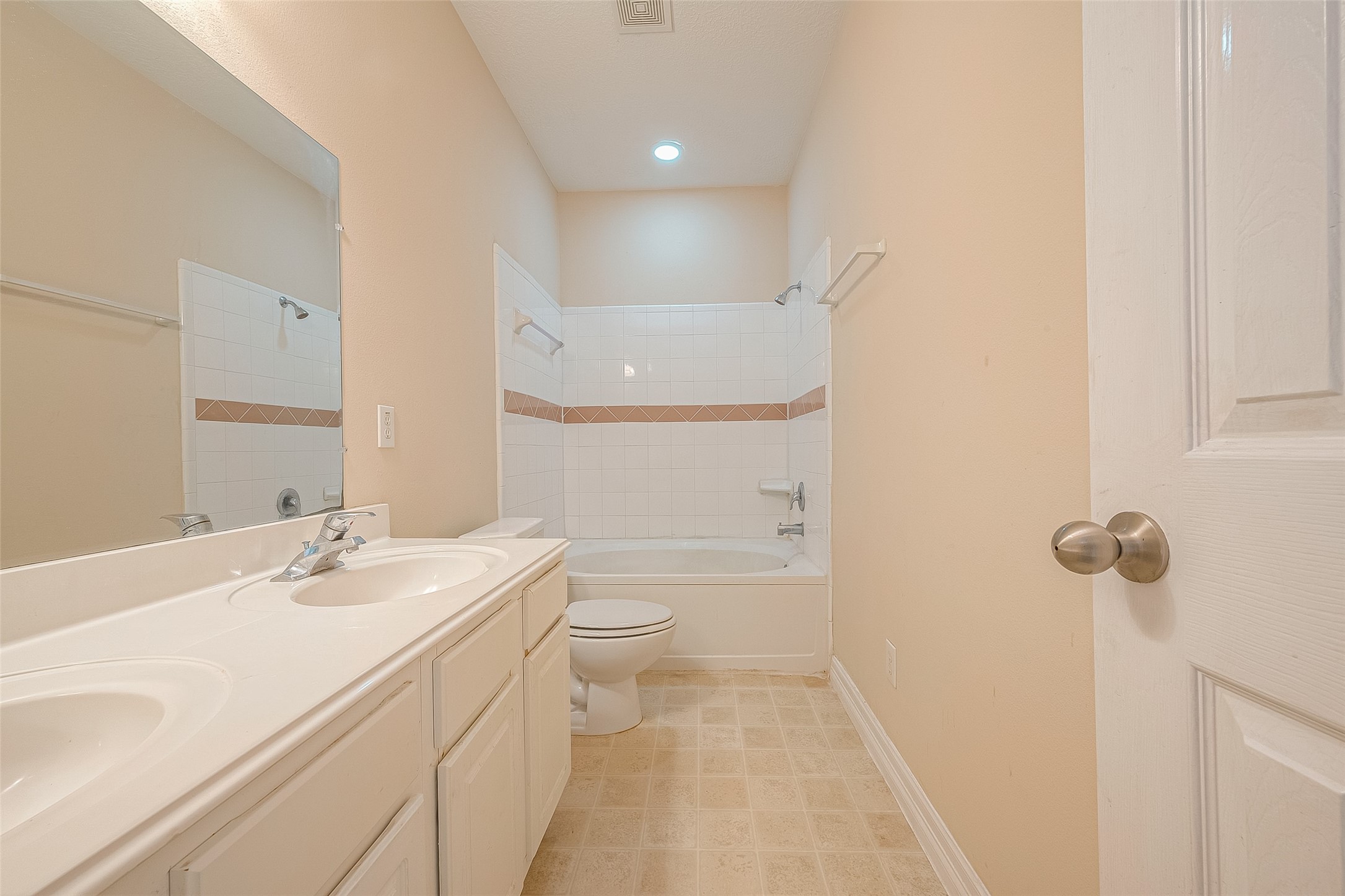 10355 Panther Point Drive Houston, TX 77099 - Photo 26 of 44 This is a bright, clean bathroom featuring a double vanity with ample storage, a large mirror, and a bathtub with a tiled shower area. The neutral color scheme and tile flooring create a fresh and inviting space.