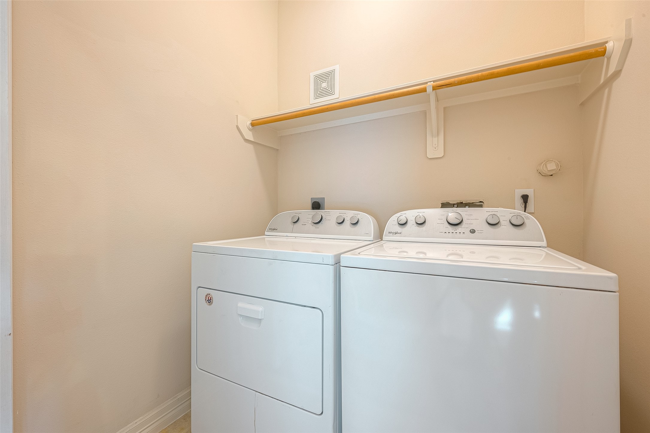 10355 Panther Point Drive Houston, TX 77099 - Photo 31 of 44 This photo shows a compact laundry area with a washer and dryer set. It has a shelf above for storage, and the room is finished with neutral-colored walls.