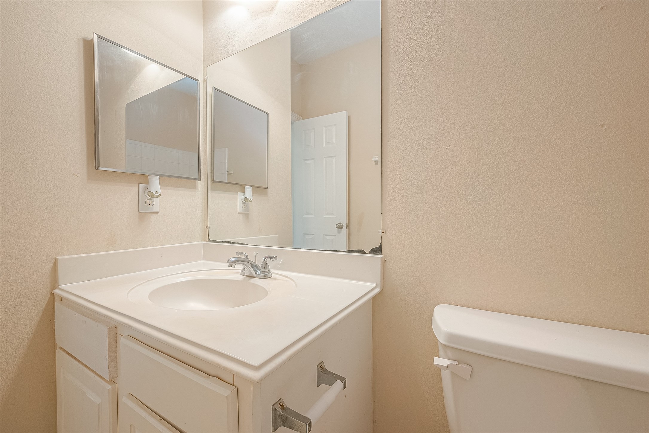 10355 Panther Point Drive Houston, TX 77099 - Photo 33 of 44 This is a compact bathroom featuring a single sink with a countertop and cabinet, a large mirror, and a toilet. The walls are painted in a neutral tone, and the space is well-lit.