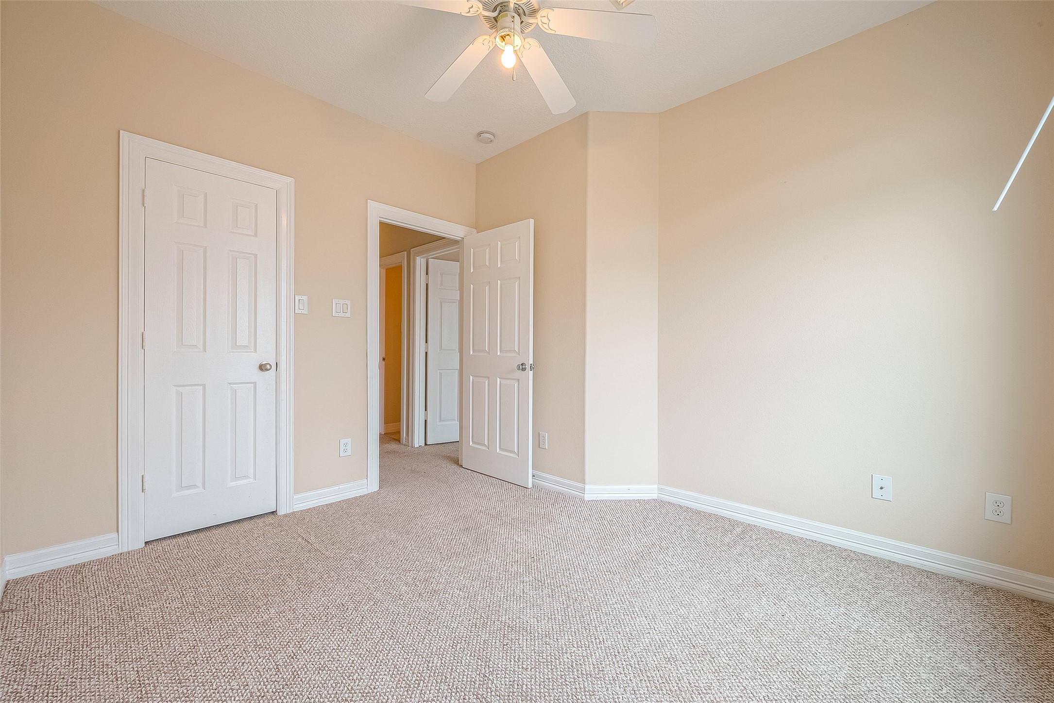 10355 Panther Point Drive Houston, TX 77099 - Photo 36 of 44 This room features neutral carpet and walls, with a ceiling fan and ample natural light. It includes two white doors, offering access to a closet and adjoining hallway.