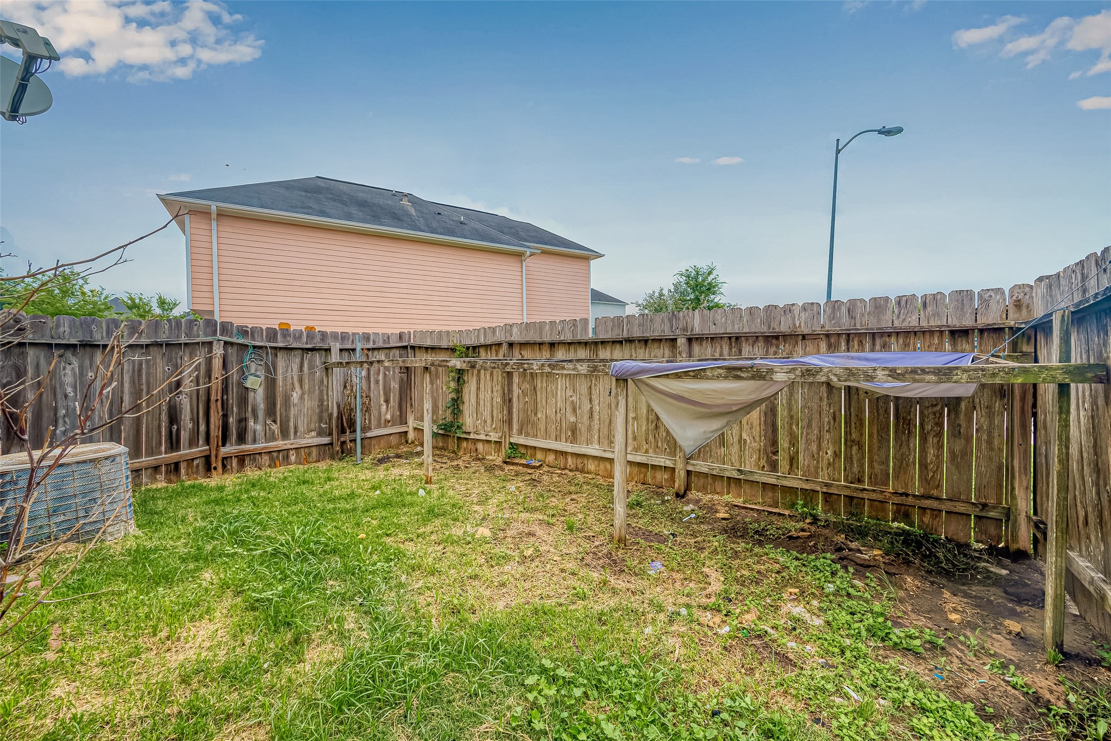 10355 Panther Point Drive Houston, TX 77099 - Photo 42 of 44 A small, fenced backyard with a grassy area, ideal for a garden or pets. There's a clothesline and an air conditioning unit, backed by neighboring houses.