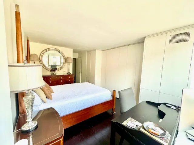 a bedroom with a bed and a dresser with wooden floor