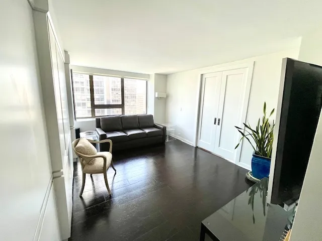 a living room with furniture floor to ceiling window and wooden floor