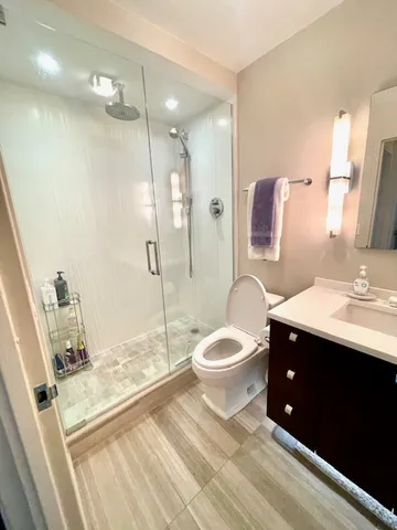 a bathroom with a sink a toilet a mirror and shower