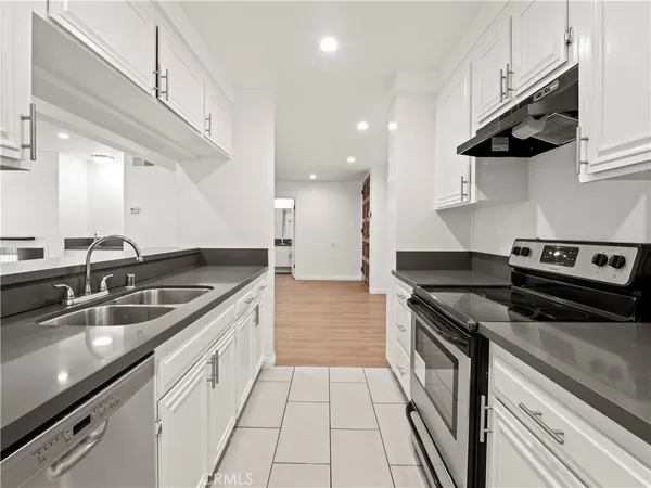 a kitchen with stainless steel appliances granite countertop a sink a stove and a wooden floors