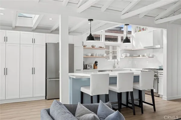 a kitchen with stainless steel appliances a dining table chairs and white cabinets