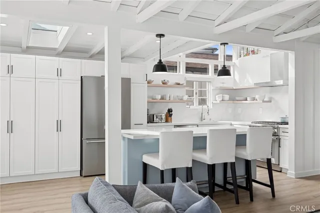 a kitchen with stainless steel appliances a dining table chairs and white cabinets