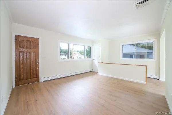 an empty room with wooden floor and windows