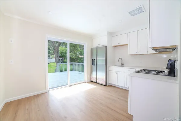 a open kitchen with granite countertop a stove top oven a sink and white cabinets with wooden floor