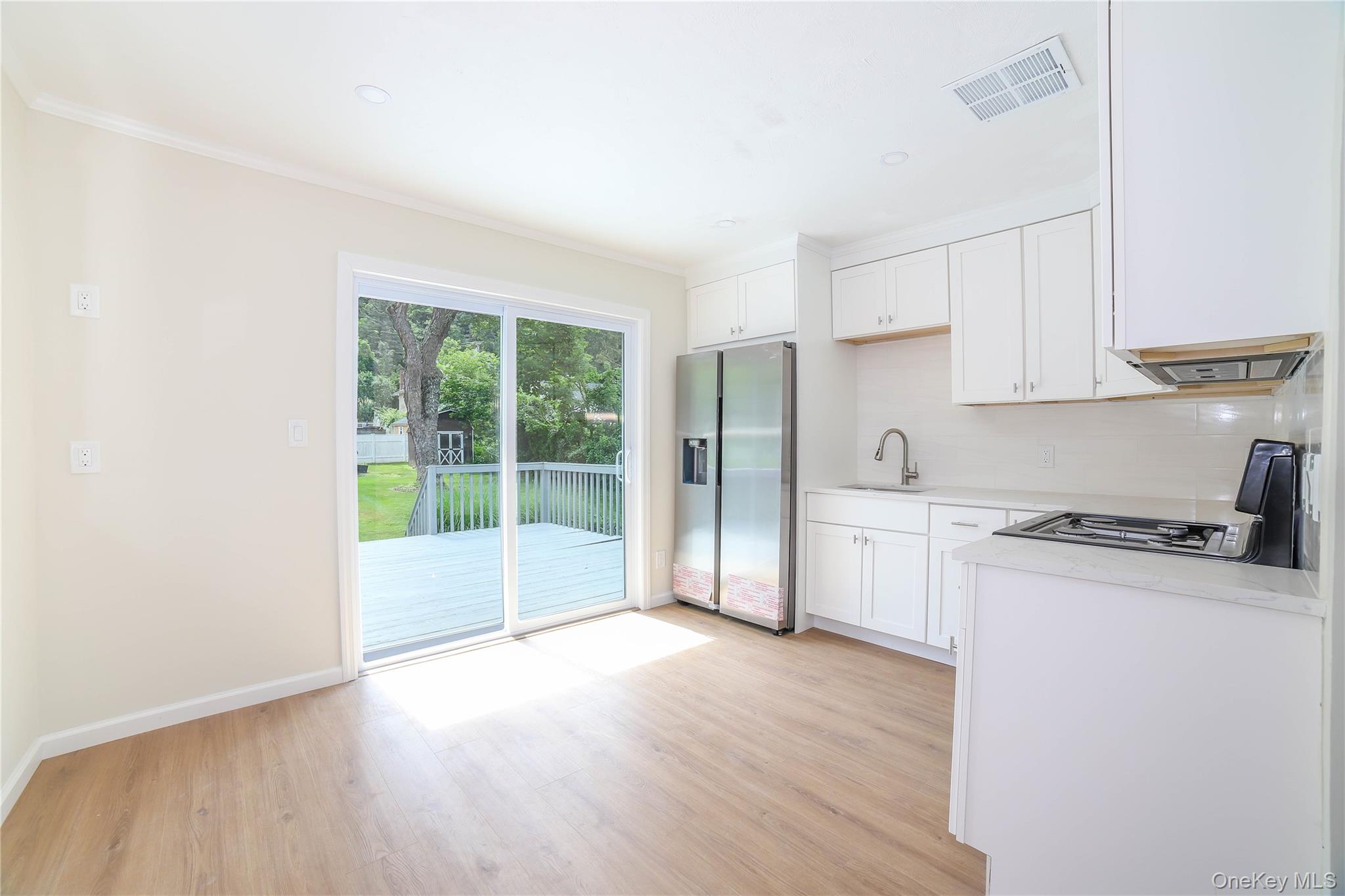 66 Putnam Road Cortlandt Manor, NY 10567 - Photo 9 of 37 a open kitchen with granite countertop a stove top oven a sink and white cabinets with wooden floor