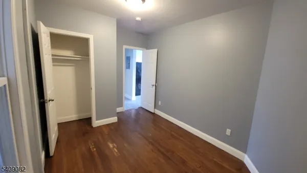 an empty room with wooden floor & closet area