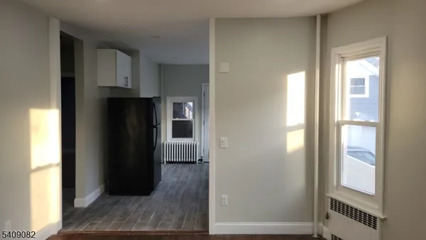 a view of hallway with wooden floor and cabinets