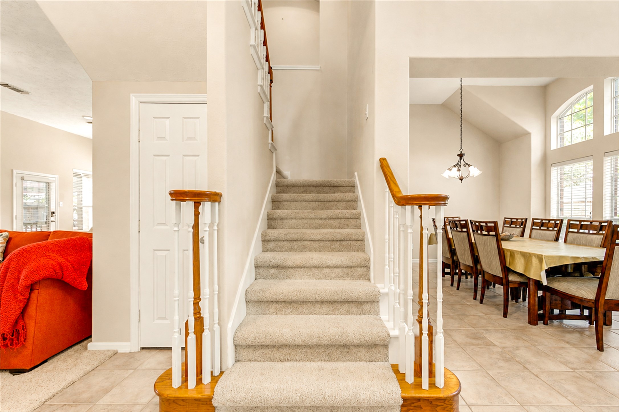 12806 Ridge Bank Lane Houston, TX 77041 - Photo 7 of 44 A bright, inviting entryway features a carpeted staircase leading to the upper level, adjacent to a spacious dining area with large windows and a modern chandelier.