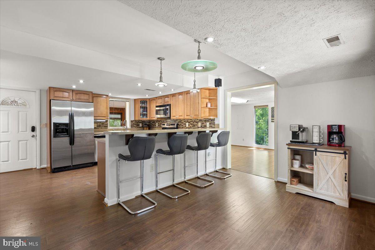 425 Mountain Road Crownsville, MD 21032 - Photo 18 of 69 a kitchen with stainless steel appliances kitchen island granite countertop a refrigerator a stove oven and white cabinets with wooden floor