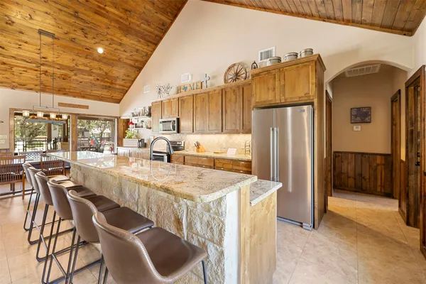 a large kitchen with stainless steel appliances kitchen island granite countertop a refrigerator and a stove
