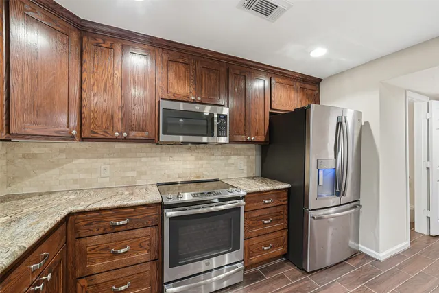 a kitchen with stainless steel appliances granite countertop a refrigerator stove and sink