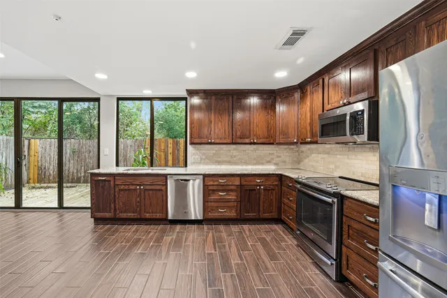 a large kitchen with stainless steel appliances granite countertop a stove a sink and a microwave