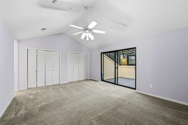 an empty room with chandelier fan and windows