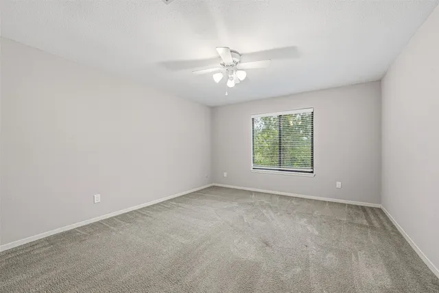 an empty room with a window and a fan