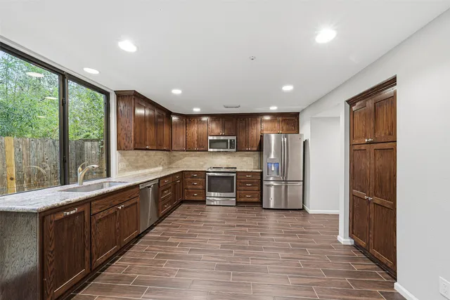 a large kitchen with stainless steel appliances wooden cabinets and a large window