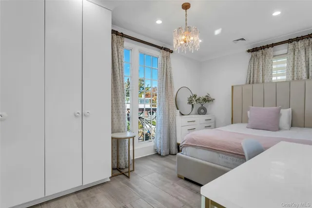 a bed sitting in a bedroom next to a window and a chandelier