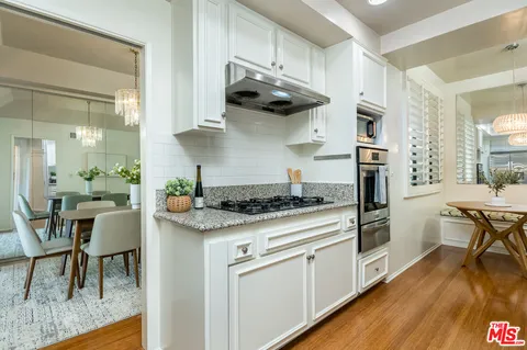 a kitchen with stainless steel appliances granite countertop a stove and a wooden floors