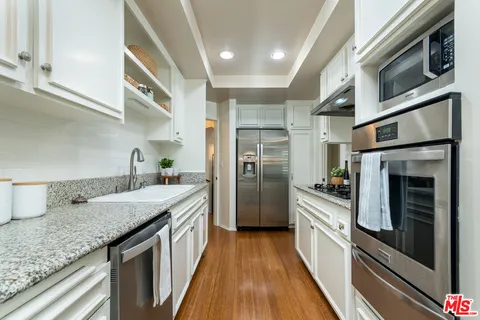 a kitchen with stainless steel appliances granite countertop a kitchen island a stove a sink and a refrigerator