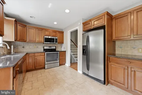a kitchen with granite countertop a refrigerator and cabinets