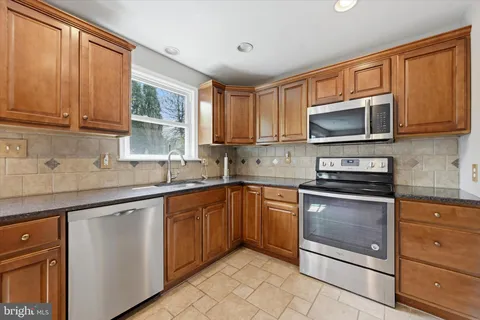 a kitchen with stainless steel appliances granite countertop a sink a stove a microwave and cabinets