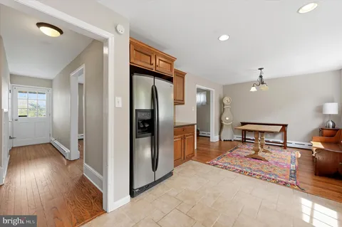 a hallway with wooden floor a glass table and chairs