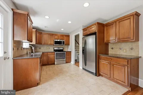 a kitchen with stainless steel appliances granite countertop a refrigerator a stove a sink a oven and a refrigerator
