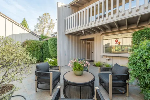 a view of a chair and table in backyard of the house
